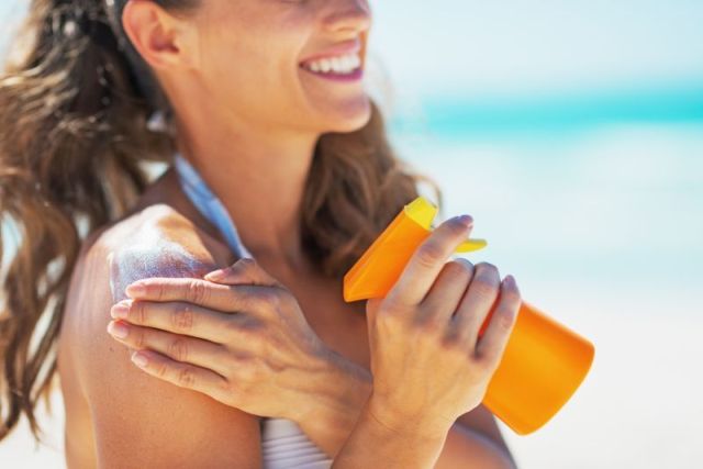 Closeup on smiling young woman applying sun block creme